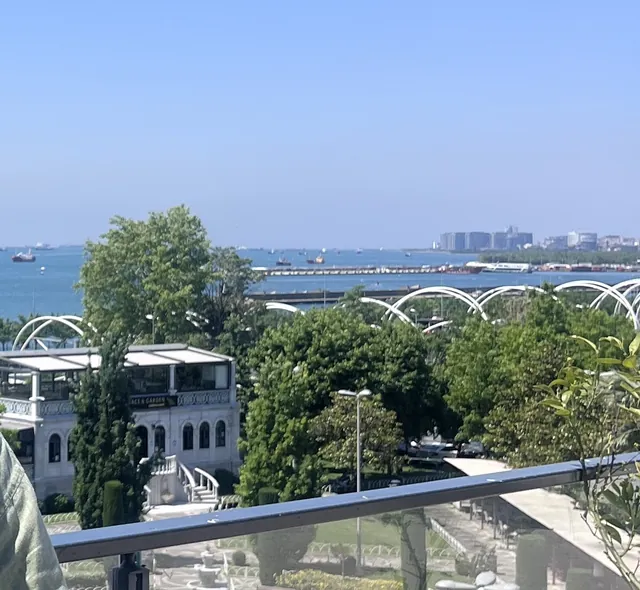 Teras korkuluğundan deniz ve park manzarası