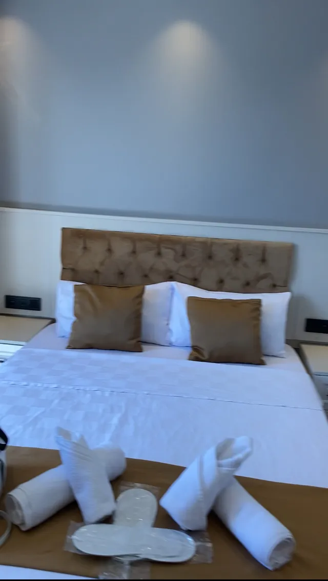 Çift kişilik yatak, kadife başlık ve havlu süslemesi